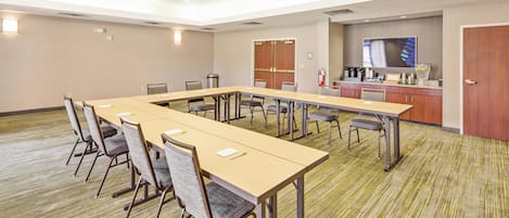 A conference room with a long table, chairs, a kitchenette, and a fire extinguisher.