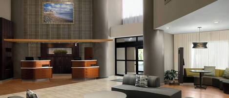 A spacious lobby with a reception desk, seating area, and a large window providing natural light.