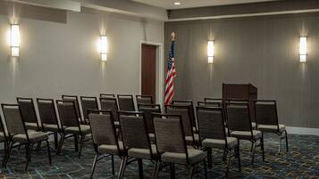 A conference room with rows of chairs, an American flag, and a podium.