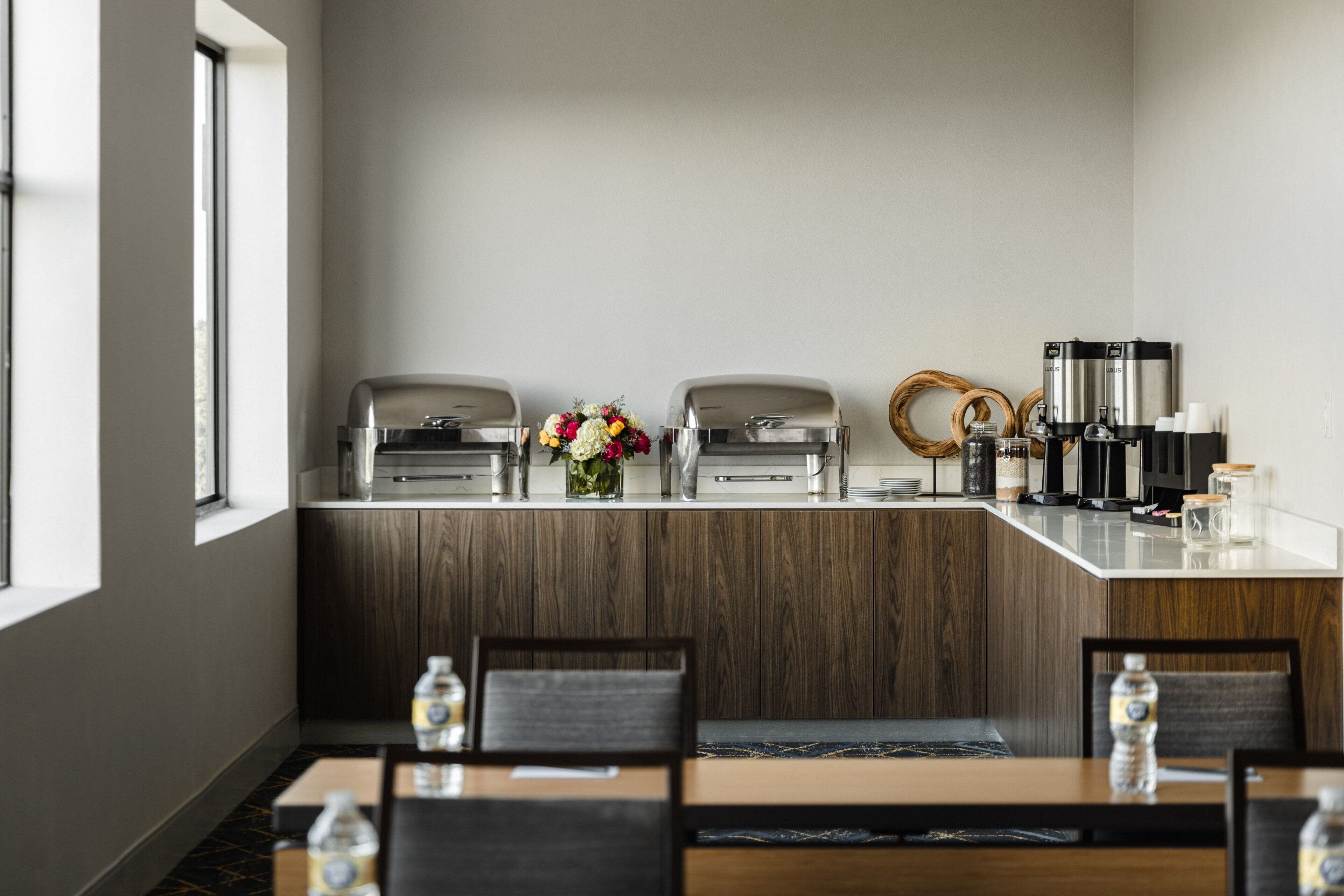 Een moderne keuken met een inbouw eiland, koffiezetapparaten en een bloemenvaas.