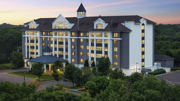 Un hotel grande de varios pisos con una torre destacada y una entrada cubierta.
