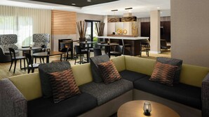 Un moderno vestíbulo de hotel con un sofá modular, comedor y bar.