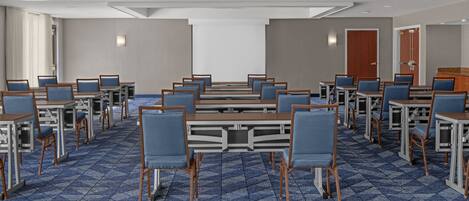 Un salón de conferencias con varias mesas y sillas dispuestas en filas.