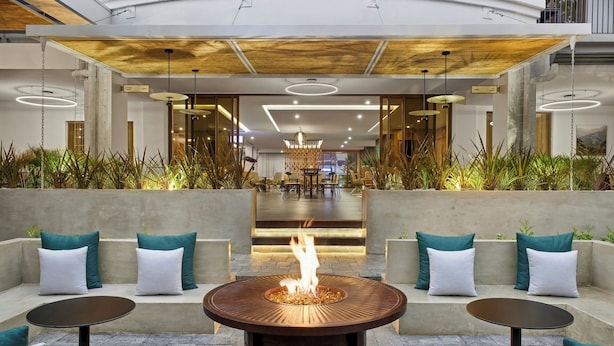Un espace extérieur moderne, aménagé avec des sièges confortables, des plantes et un foyer central.