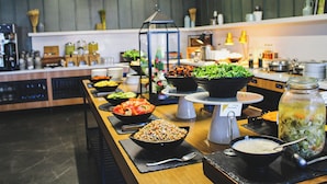 Un buffet proposant une variété de plats, notamment des salades, des soupes et des céréales, dans un cadre de cuisine moderne.