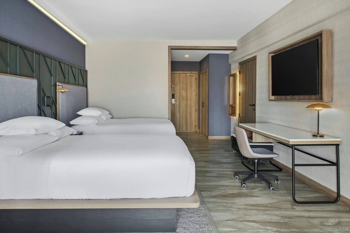 Een hotelkamer met een groot bed, een bureau met stoel, een flatscreen televisie en een houten deur.