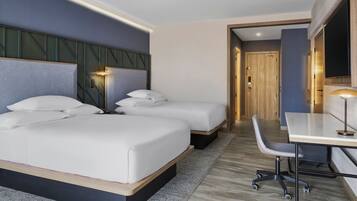 A modern hotel room with a large bed, a desk, and a chair.