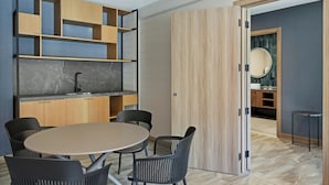 Une cuisine moderne dotée d’un plan de travail en marbre, de meubles en bois et d’une table de salle à manger ronde avec des chaises noires.