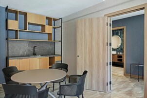 A modern kitchen with a marble countertop, wooden cabinets, and a round dining table with black chairs.