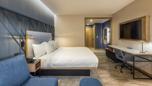 Une chambre d’hôtel moderne, dotée d’un grand lit, d’un bureau et d’un coin salon.
