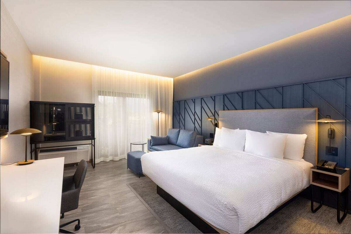 Een moderne hotelkamer met een groot bed, een bureau, een stoel, een bank en een televisie.