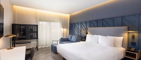 Een moderne hotelkamer met een groot bed, een bureau, een stoel, een bank en een televisie.