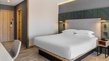 A modern hotel room with a large bed, a desk, and a chair.