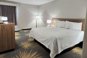 A hotel room with a large bed, a desk, and two bedside lamps. - Days Inn by Wyndham LaPlace- New Orleans (LaPlace)