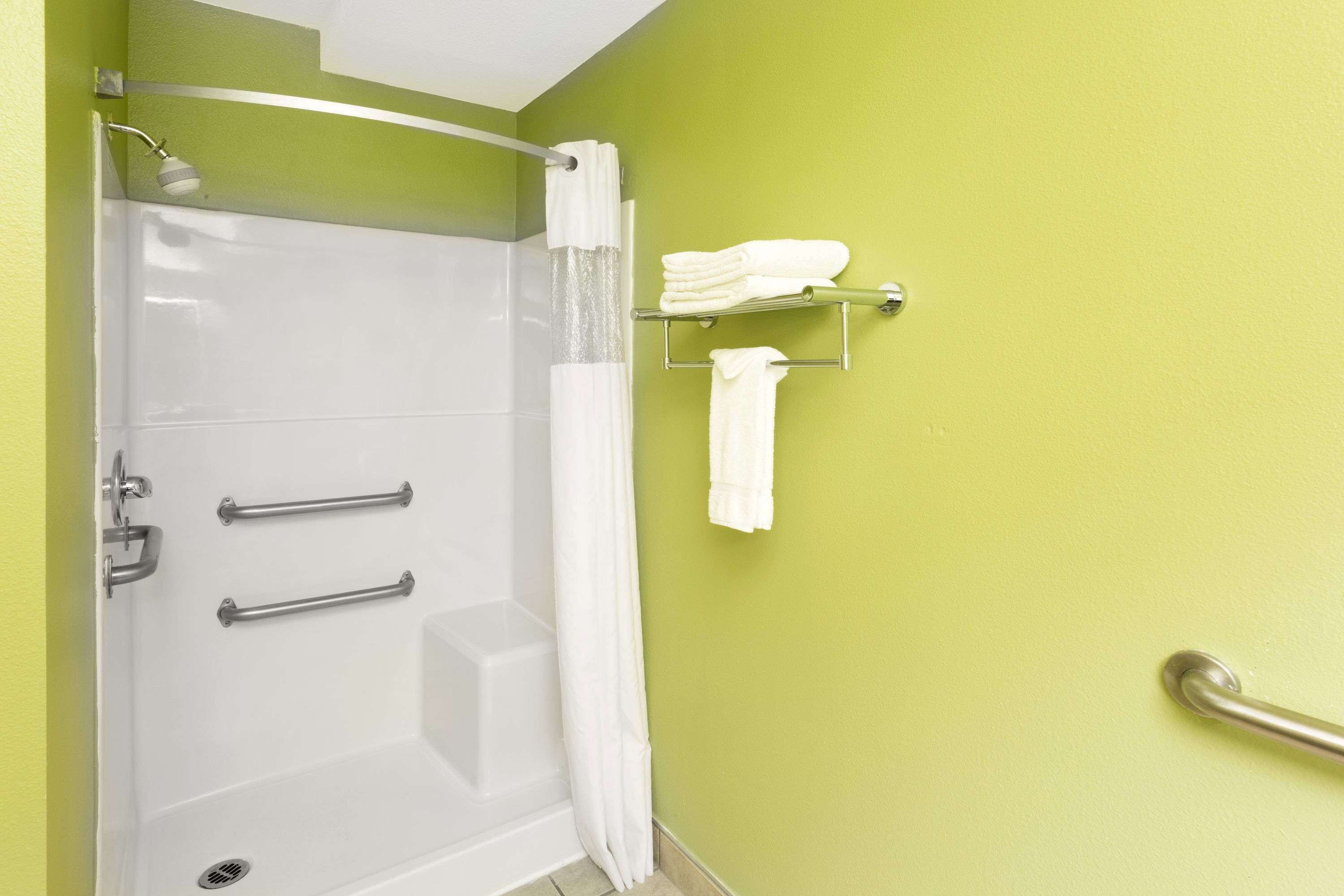 Un bagno con doccia, maniglie di sostegno e porta asciugamani.