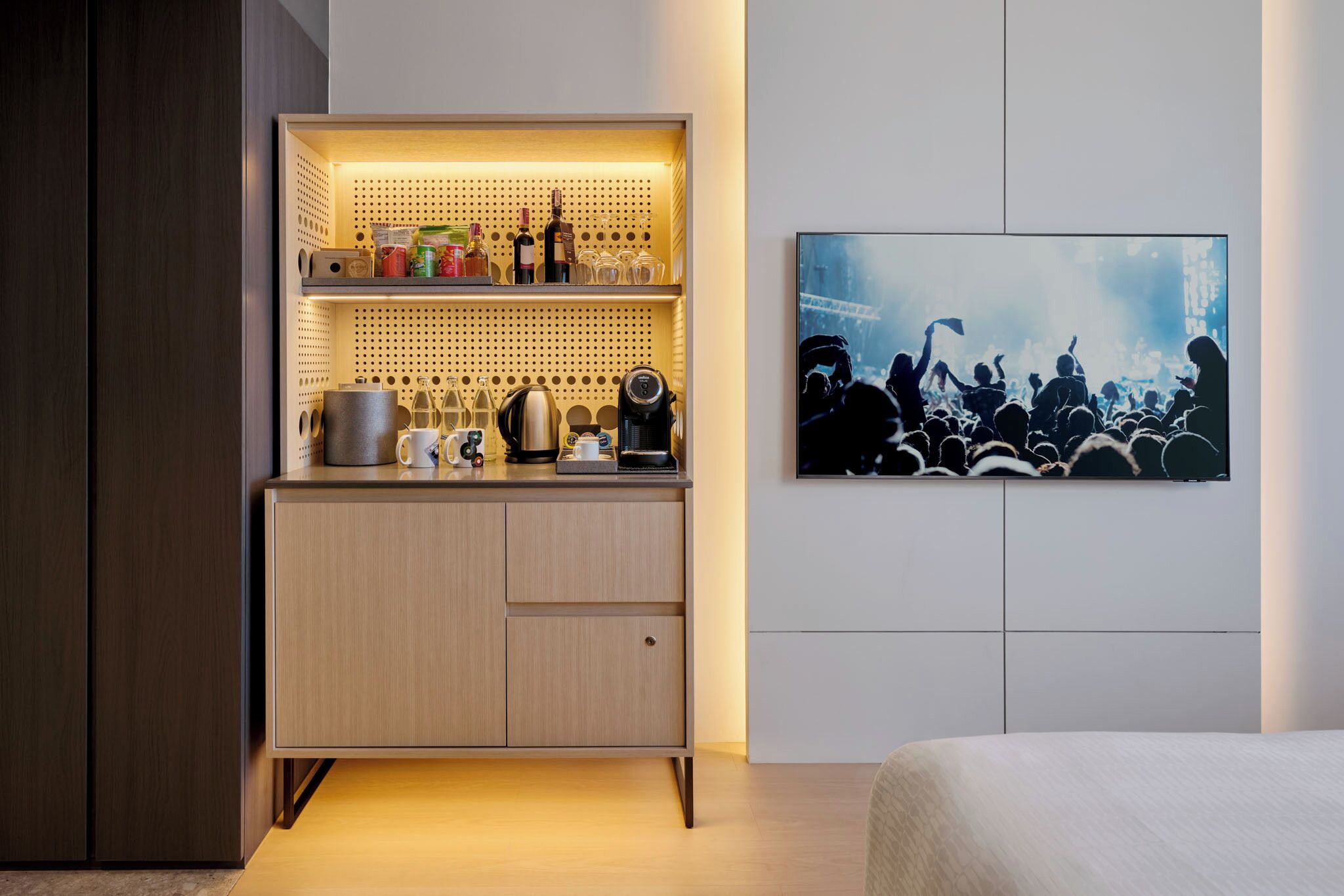 A modern room with a built-in kitchen area, a bed, and a large abstract painting on the wall.