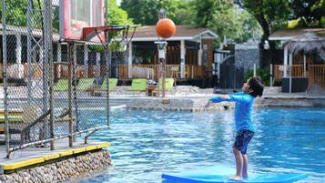 A person on a blue floating platform in a pool with a basketball hoop and net in the background.