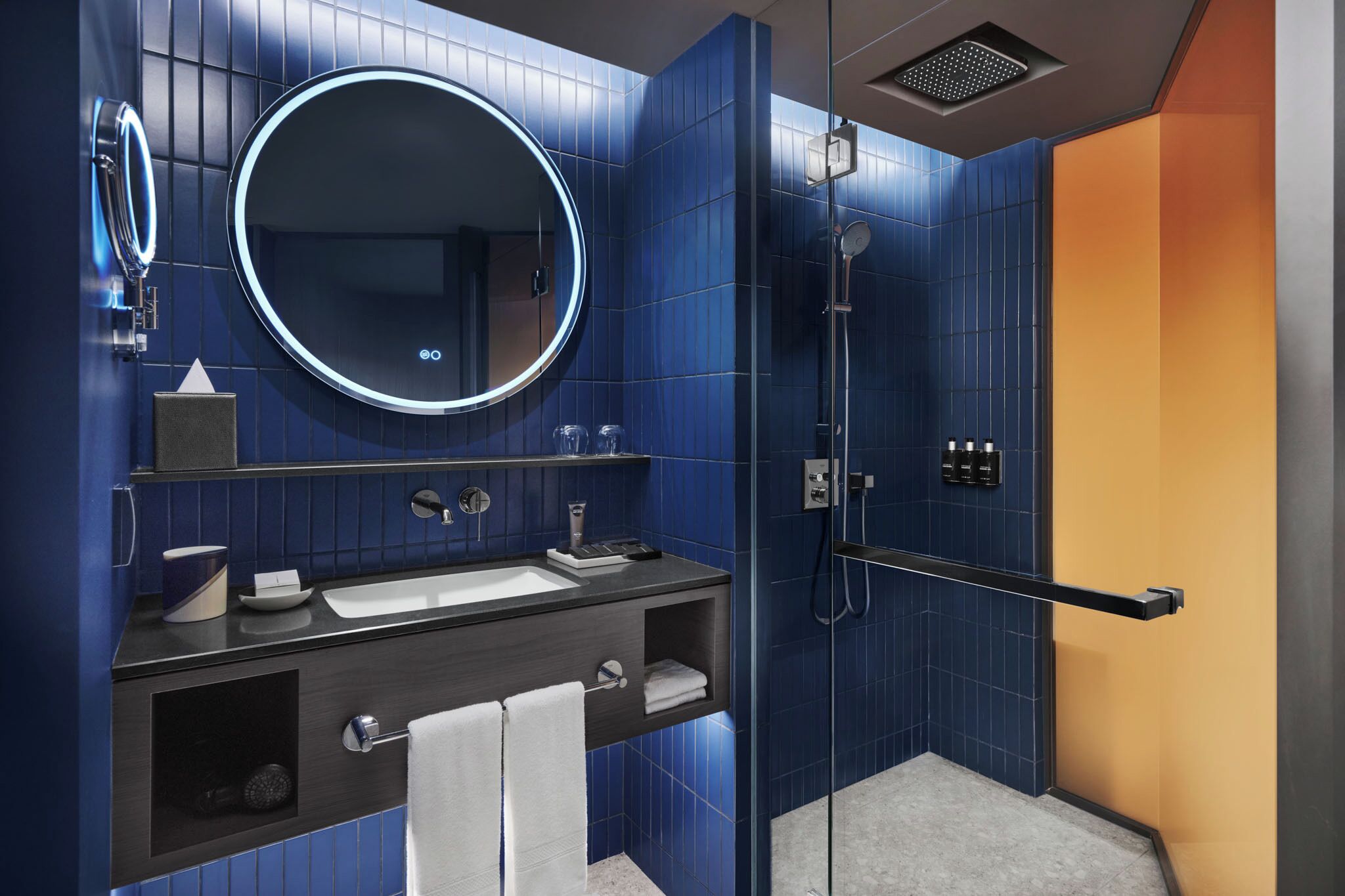 A modern bathroom with a large mirror, a sink, a shower, and a towel rack.