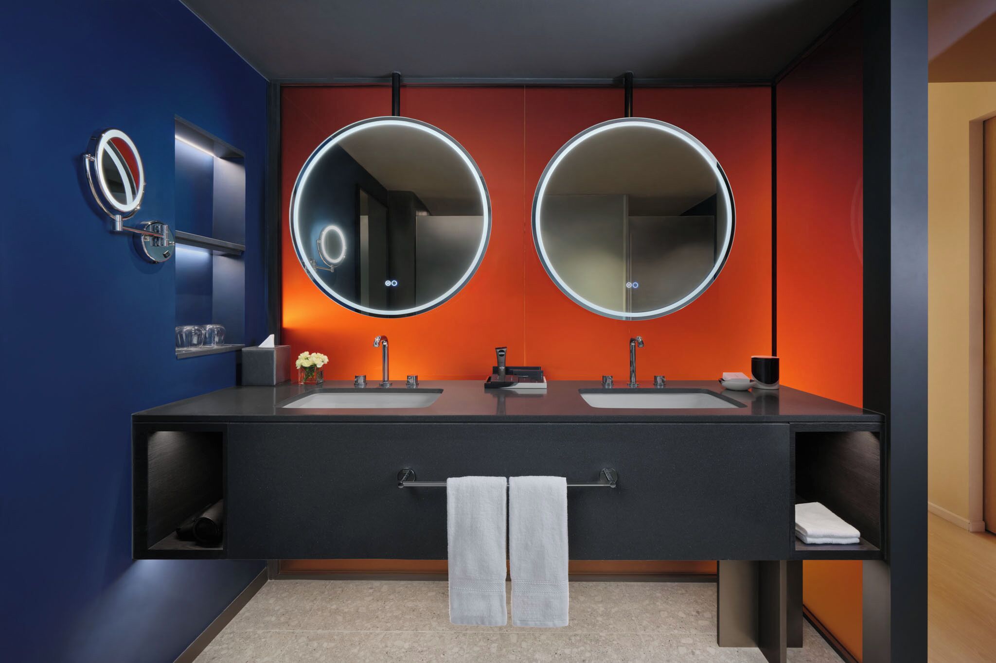 Un baño moderno con dos lavamanos, un espejo grande y un perchero para toallas.