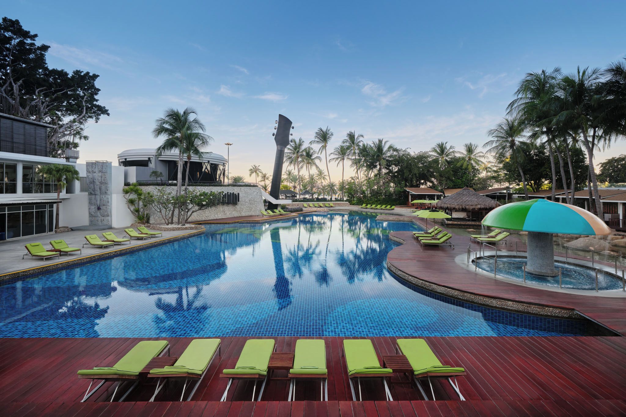 A swimming pool with lounge chairs, palm trees, and modern buildings.