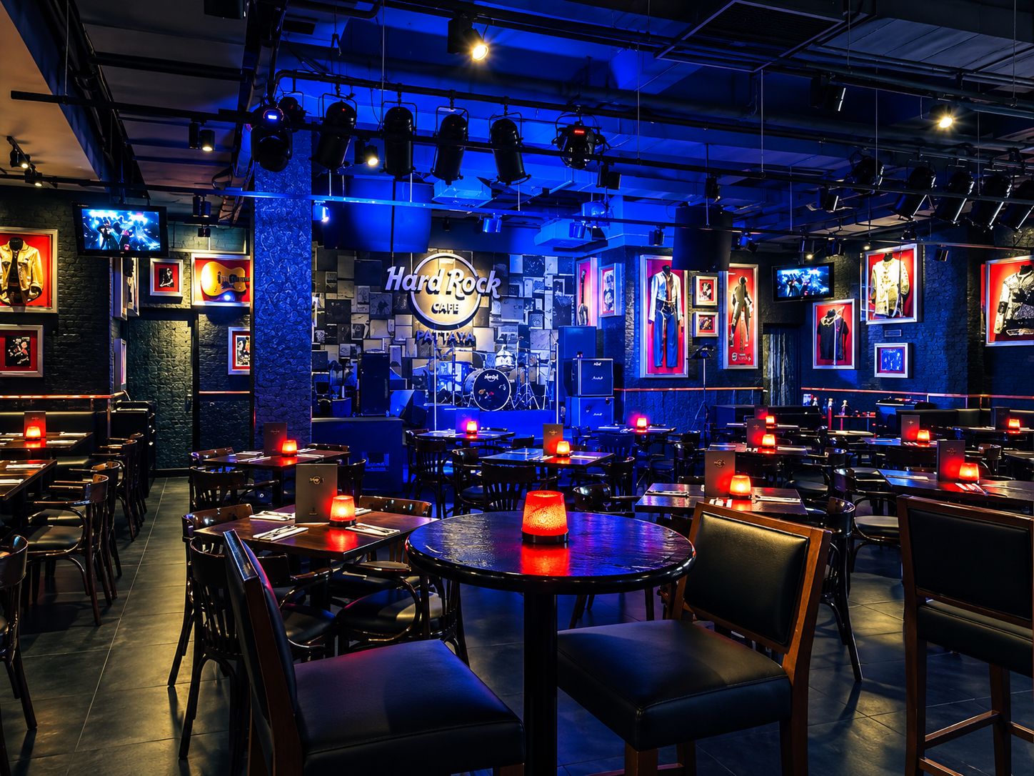 Interior de Hard Rock Cafe con varias mesas, sillas y un área de escenario.