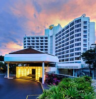 Un hotel con un letrero llamativo, un acceso cubierto y un edificio grande de varios pisos.