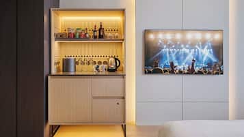 A modern hotel room with a built-in minibar, a flat-screen TV on the wall, and a bed.