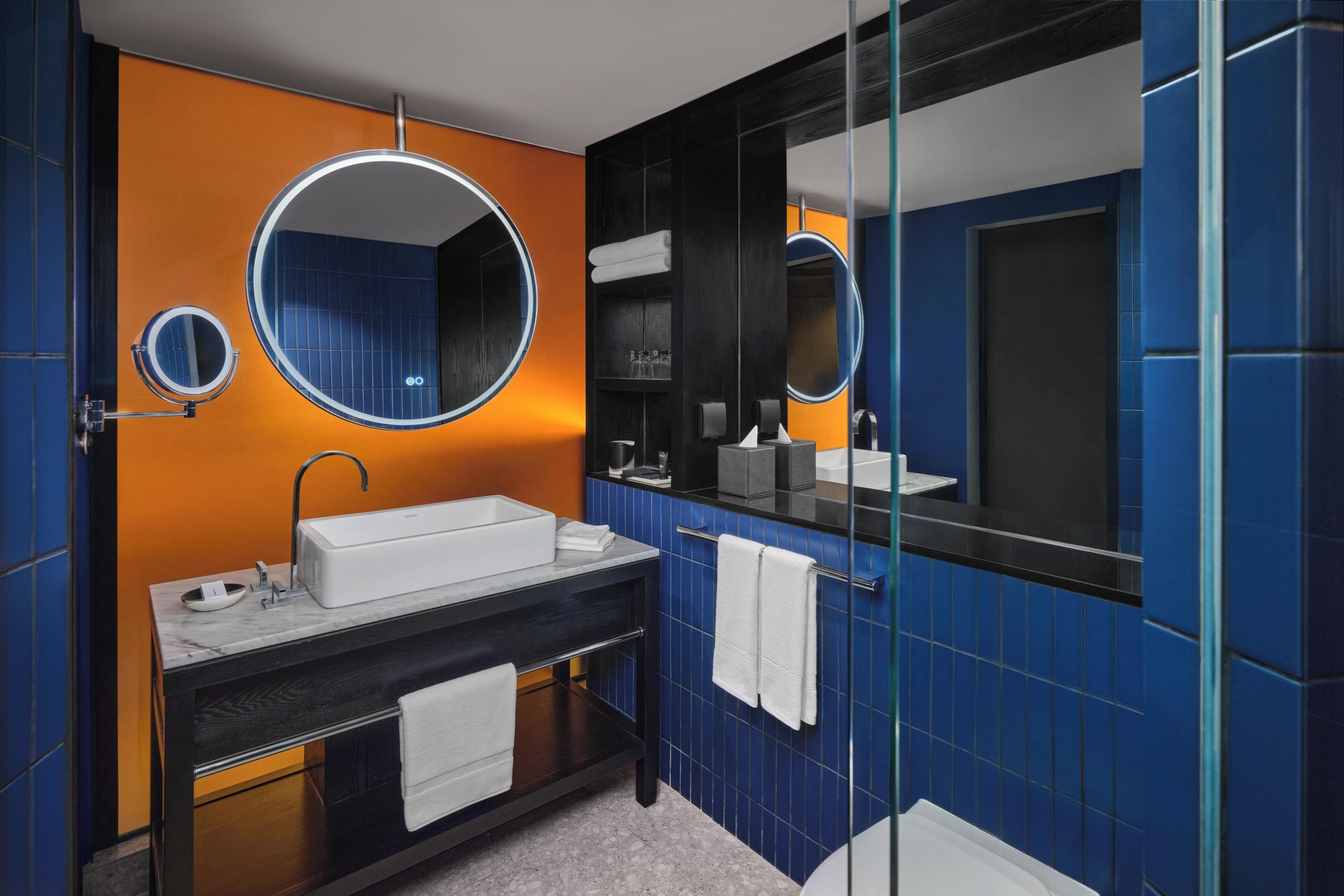 A modern bathroom with a large mirror, a sink, and a glass shower enclosure.