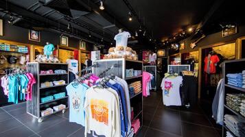 A clothing store with racks of clothes, a teddy bear display, and a sign indicating a kids section.