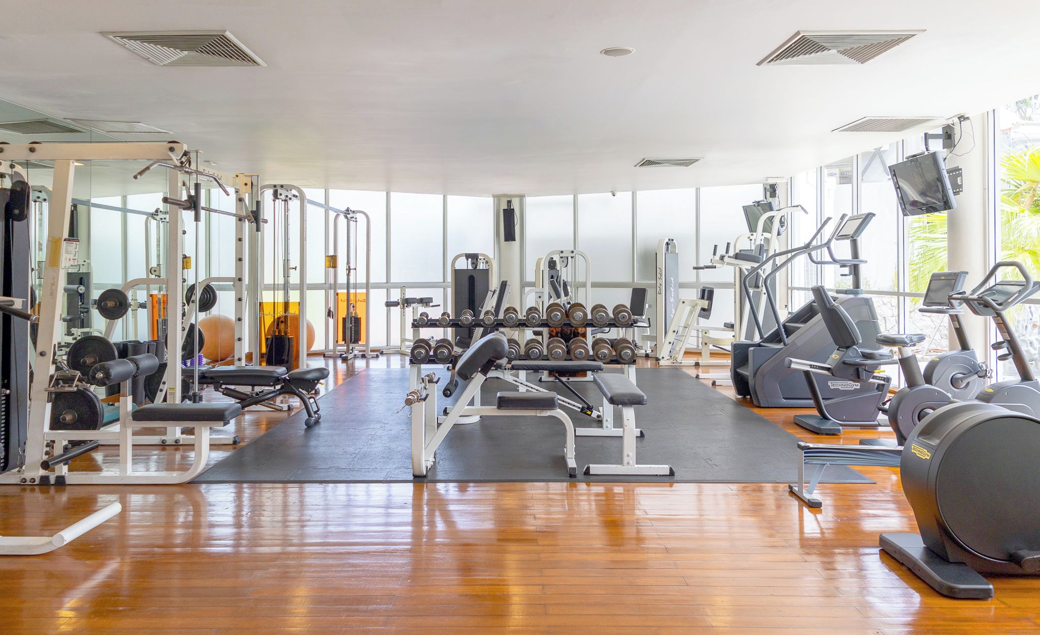 Une salle de sport équipée de divers appareils d’exercice, notamment des tapis de course, des appareils de musculation et des poids libres.