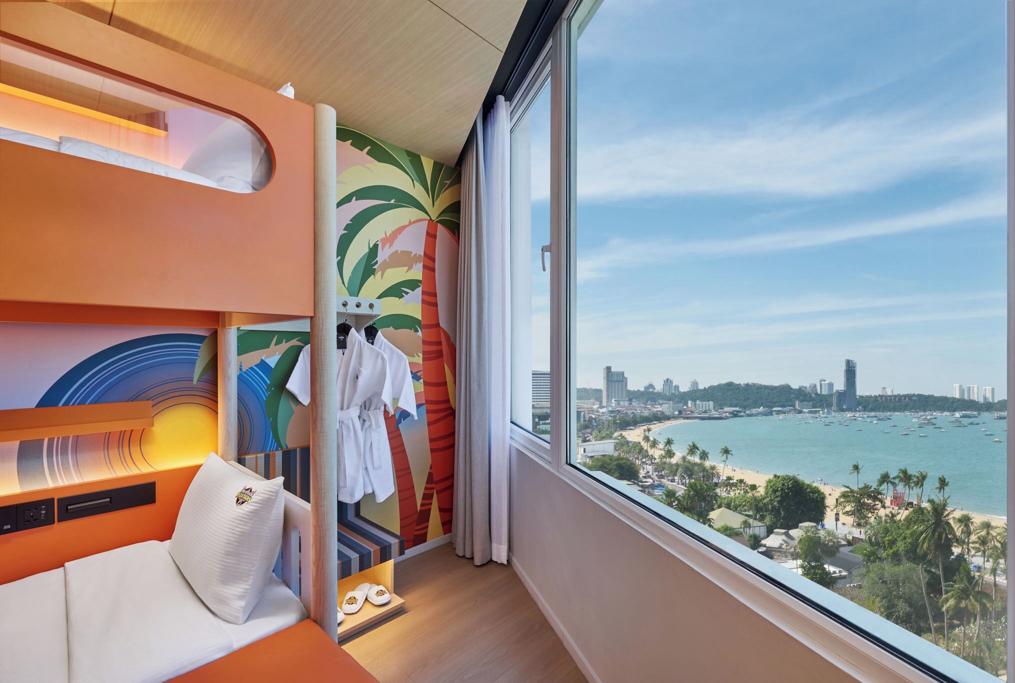 Une chambre d’hôtel comprenant un lit, un coin salon, une vue sur la plage et un panorama sur la ville.