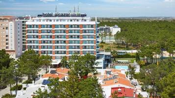 Ein Hotel mit mehreren Etagen, einem Dachpool und umgebender Bepflanzung.