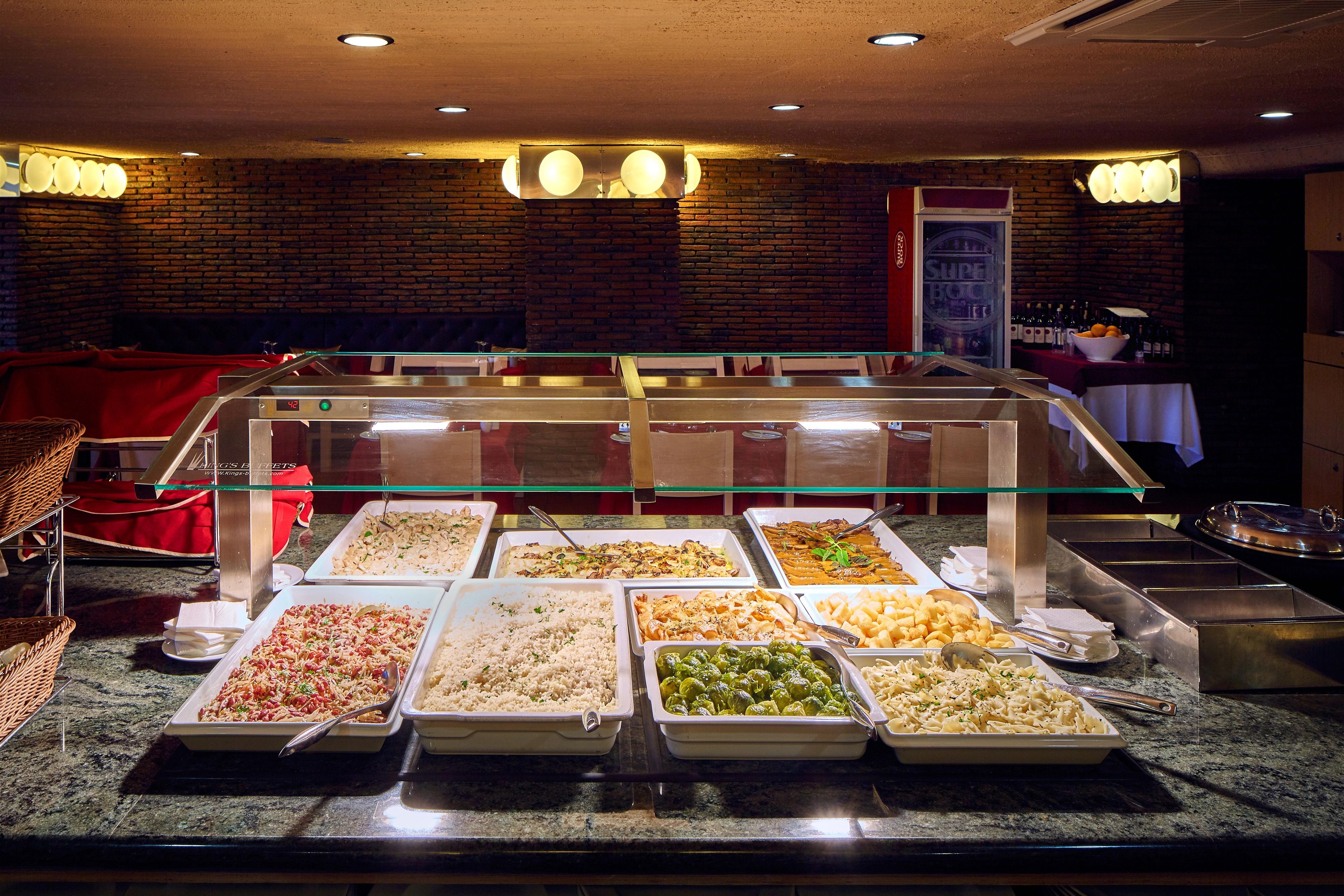 Buffet amb diverses opcions de menjar, un mur de maó de fons i un cartell que diu 'SUPER BOWL'.