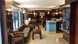 A spacious living area with a sofa, armchairs, a coffee table, and a small bar area with decorative items. - Club Hotel (Mestre)