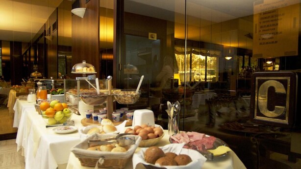 A buffet setup with various food items and a glass partition. - Club Hotel (Mestre)