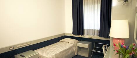Une chambre d’hôtel avec deux lits, un bureau, une chaise, une télévision et une fenêtre avec des rideaux.