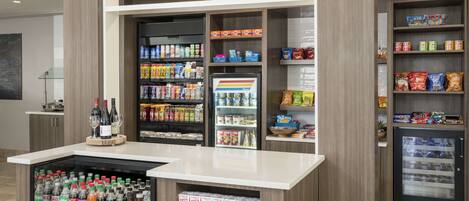 Eine Selbstbedienungsstation für Getränke mit gekühlten Getränken, Snacks und verschiedenen Flaschenwasser- und Limonadesorten.