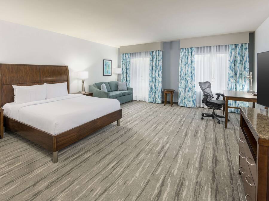 Een hotelkamer met een groot bed, een bureau, een stoel en een televisie.