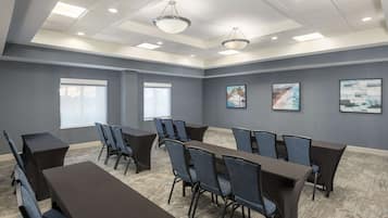 A conference room with a long table and chairs, large windows, and artwork on the walls.