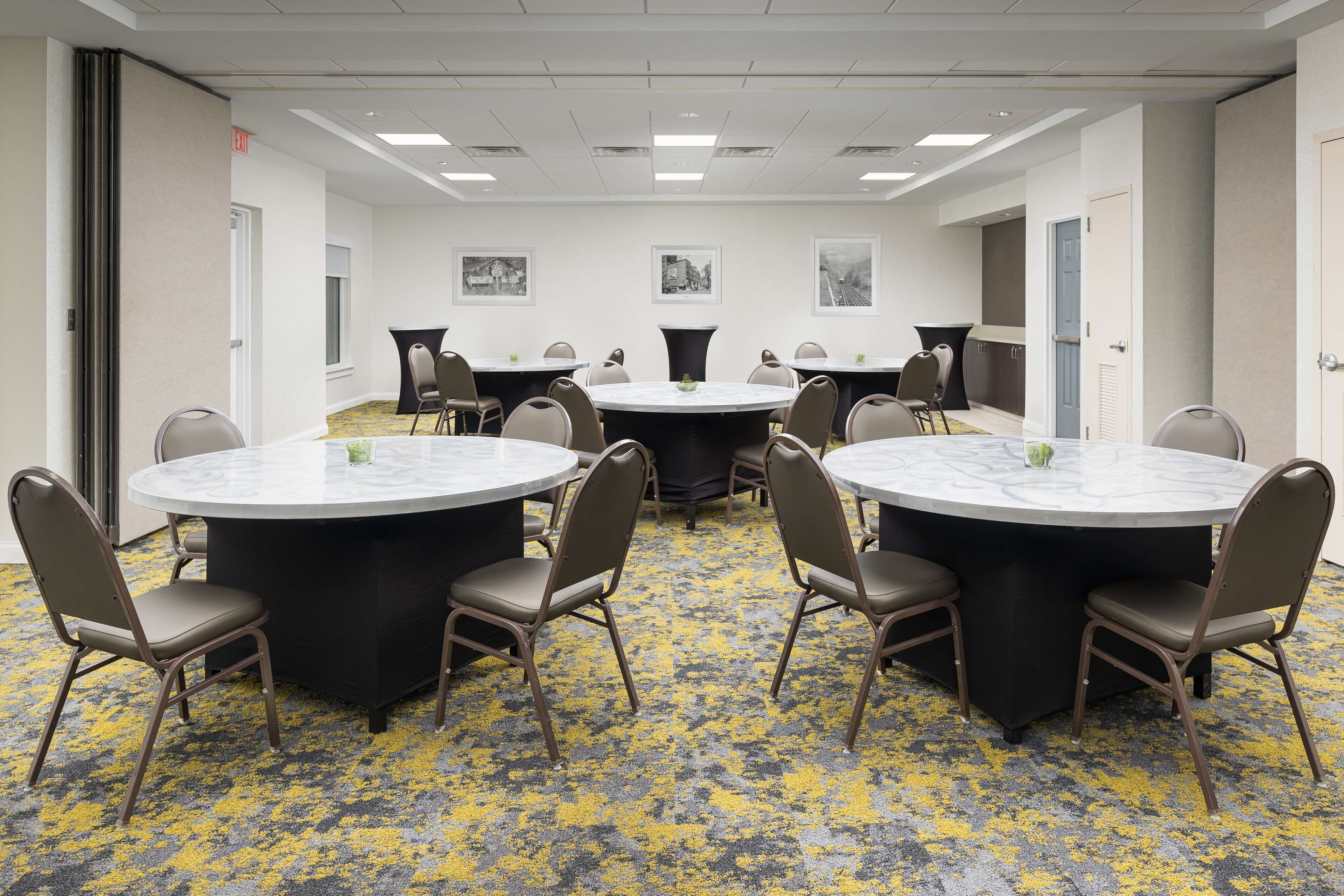 A conference room with round tables, chairs, and a patterned carpet.