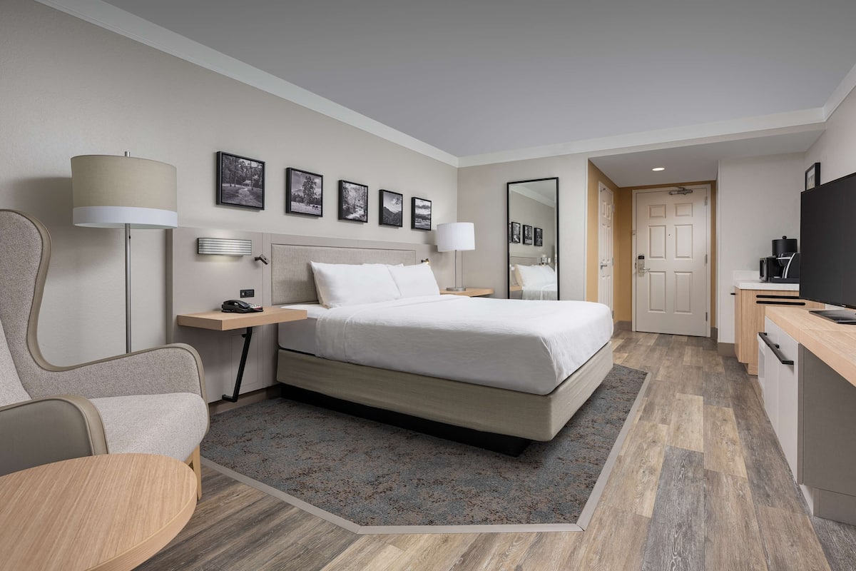 Moderni hotellihuone, jossa on suuri sänky, yöpöydät, työpöytä ja tuoli.