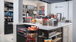 Et moderne caféinteriør med en selvbetjeningsstation til drikkevarer, en snackbar og et udvalg af mad.