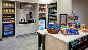 Una cafetería con estantes de aperitivos, una máquina de café y una sección refrigerada.