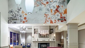 Un vestíbulo espacioso con chimenea, zona de estar y un amplio mural floral en el techo.