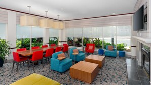 Uma área de estar moderna com uma mesa de madeira, cadeiras vermelhas e azuis e um sofá amarelo.