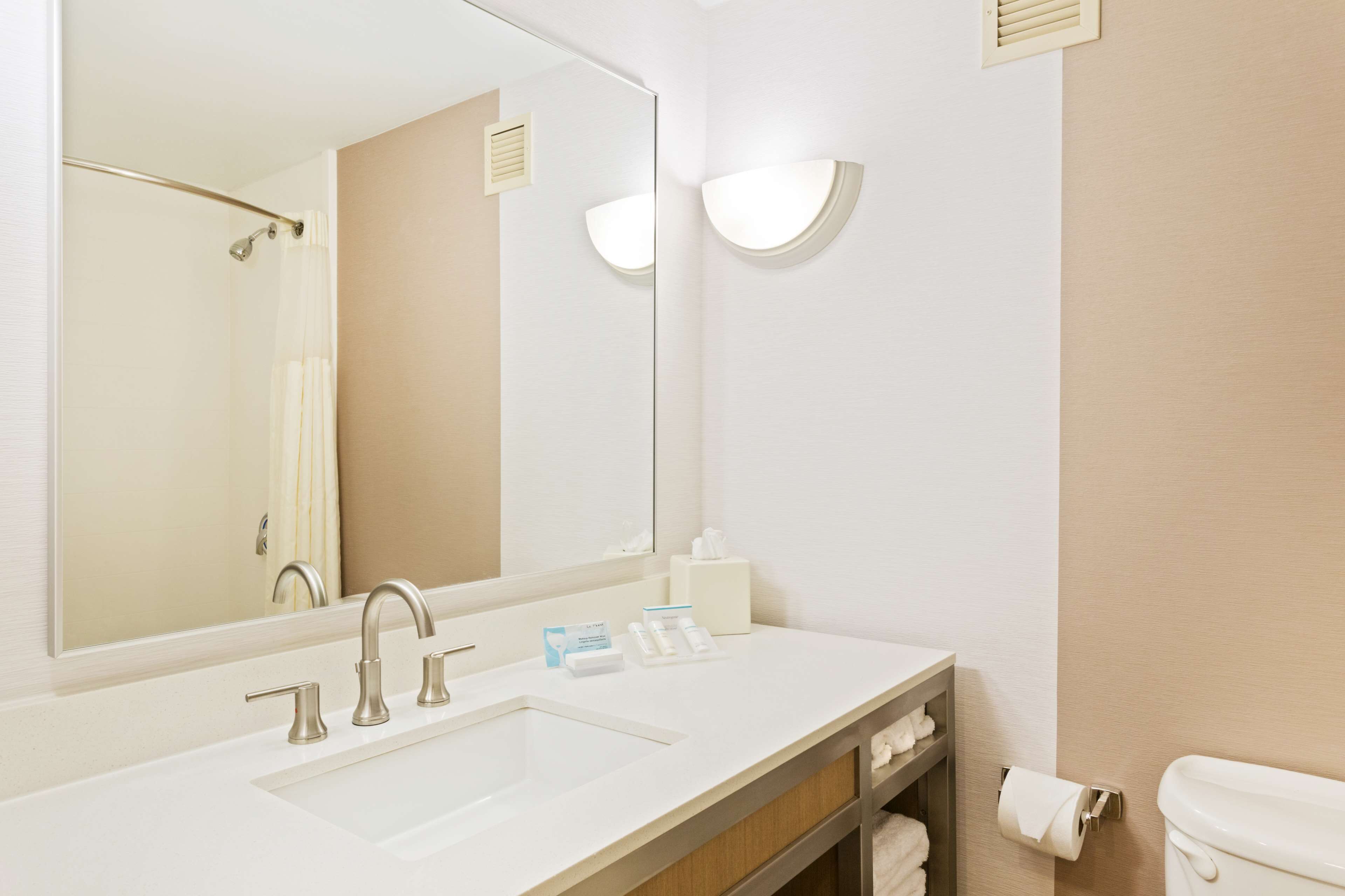 Un baño moderno con un lavamanos blanco, un espejo grande y un inodoro.