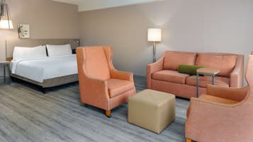 Una habitación de hotel con una cama, dos sillones, un sofá, una mesita y una lámpara.