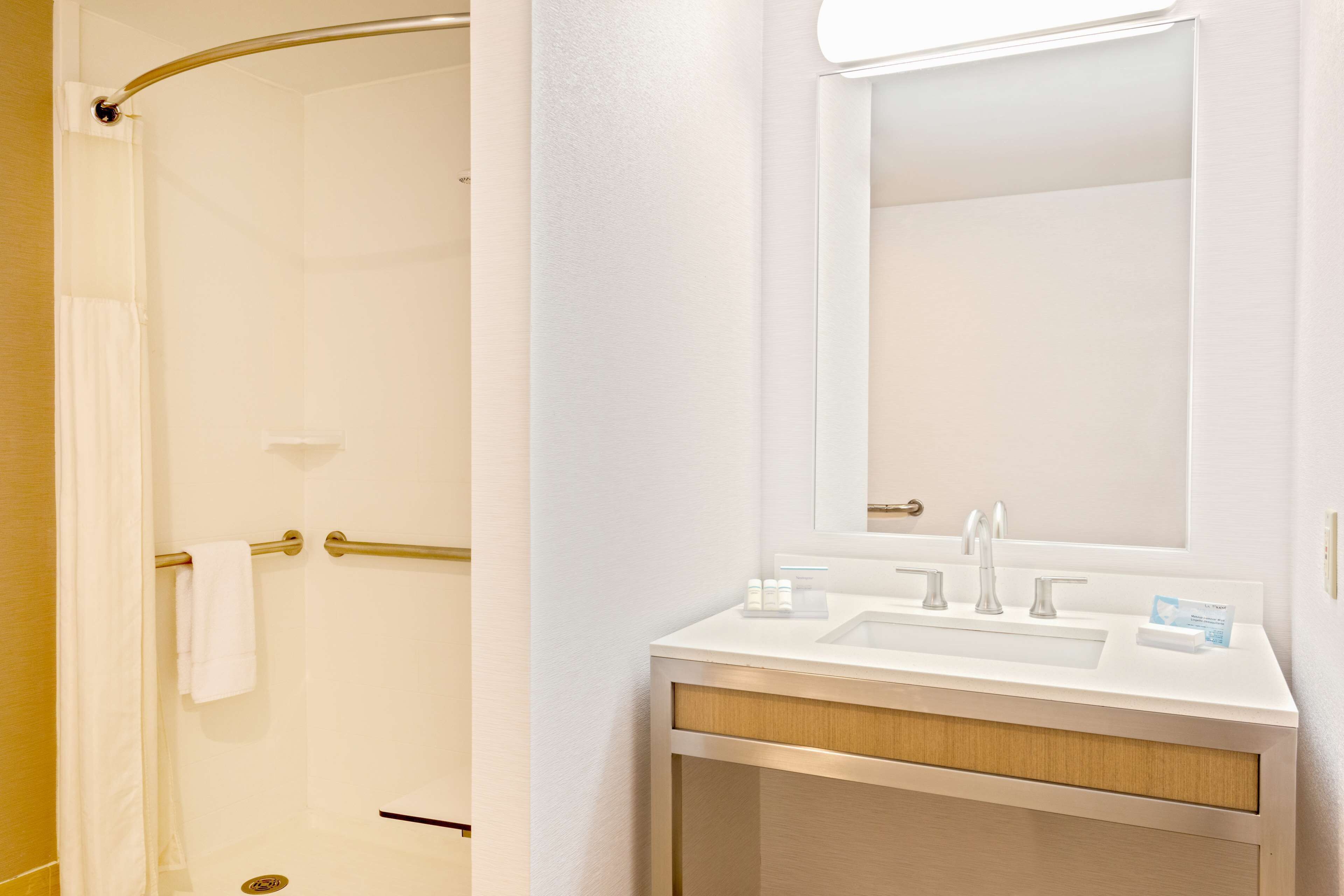 A bathroom with a shower, a sink, and a mirror.
