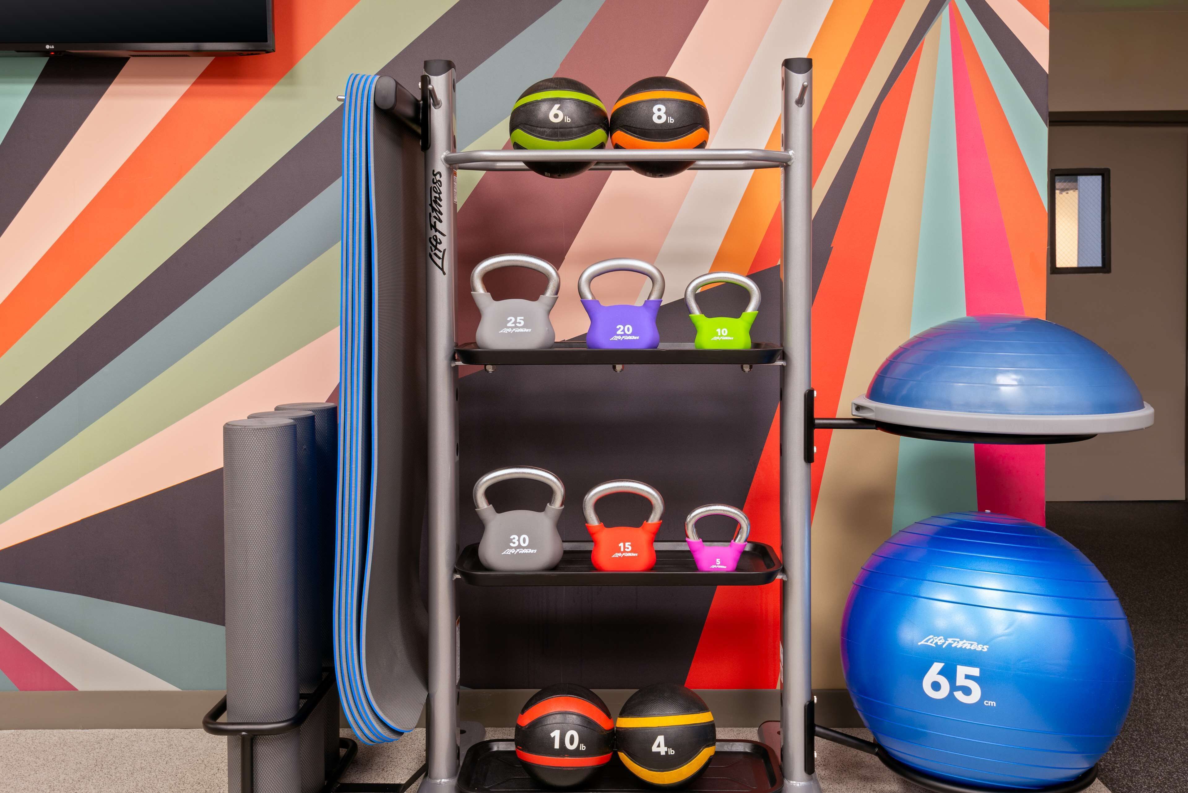 Ein Fitnessbereich mit Gewichtsbank, Kettlebells und Trainingsbällen.