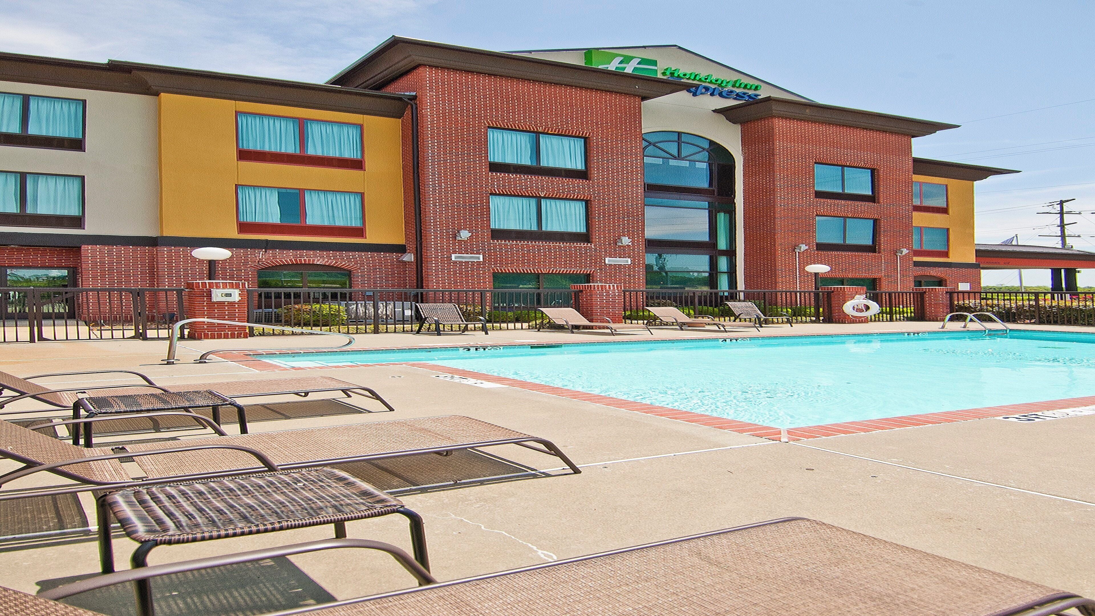 A hotel with a pool area, including lounge chairs and a lifeguard stand.